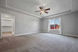 Master bedroom featuring a tray ceiling, ceiling fan, and baseboards