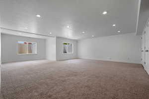 Unfurnished room featuring light carpet, recessed lighting, baseboards, and a textured ceiling