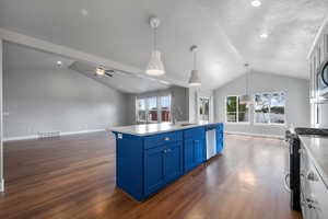 Kitchen featuring blue cabinets, appliances with stainless steel finishes, vaulted ceiling, a sink, and open floor plan