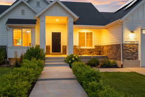 View of front facade featuring board and batten siding, stone siding, and a shingled roof
