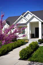 View of front of home with roof with shingles, board and batten siding, and stone siding