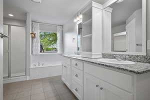 Master Bathroom with double vanity, a bath, a shower stall, and tile patterned floors