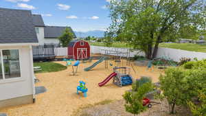 View of playground with a trampoline, a mountain view, and a fenced backyard