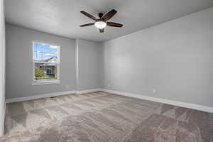 Spare room with carpet floors, a ceiling fan, and baseboards