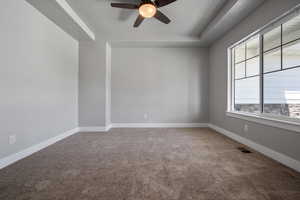 Office/Den with a tray ceiling, carpet floors, ceiling fan, and baseboards
