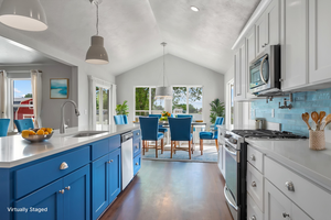 Kitchen with stainless steel appliances, a sink, light countertops, blue cabinets, and lofted ceiling