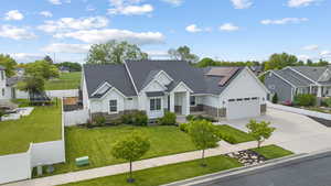 View of front of house with stone siding, board and batten siding, concrete driveway, roof mounted solar panels, and a garage