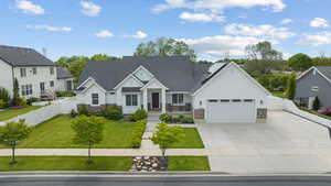 View of front of house featuring board and batten siding, stone siding, driveway, a garage, and roof mounted solar panels