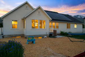 Rear view of house featuring roof mounted solar panels and stucco siding