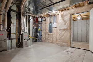 Unfinished below grade area featuring secured water heater and electric panel