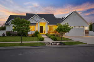 View of front of house with board and batten siding, stone siding, driveway, solar panels, and a garage