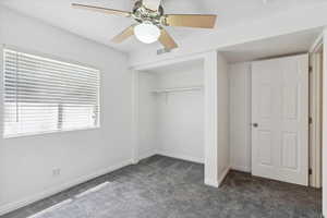 Unfurnished bedroom with carpet flooring, a closet, baseboards, and a ceiling fan
