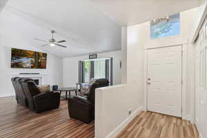 Foyer entrance with light wood finished floors, lofted ceiling, a chandelier, baseboards, and ceiling fan