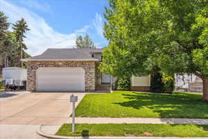 View of front of house featuring driveway, a garage, a front yard, and a shingled roof