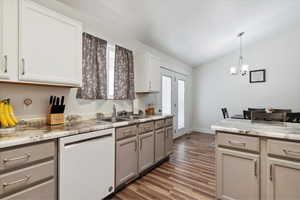 Kitchen featuring white dishwasher, a sink, a chandelier, wood finished floors, and gray cabinets