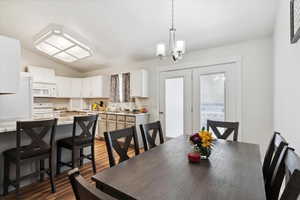 Dining room with a chandelier, wood finished floors, and vaulted ceiling