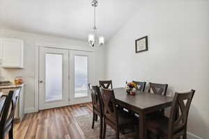 Dining room with light wood-type flooring, a chandelier, and baseboards