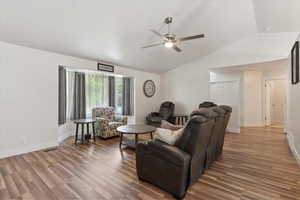Living room with vaulted ceiling, a ceiling fan, wood finished floors, and baseboards