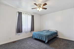Carpeted bedroom with ceiling fan and baseboards