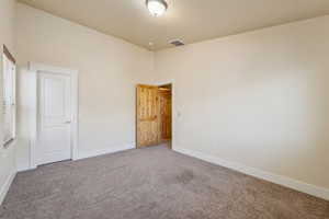 Unfurnished bedroom with carpet flooring, baseboards, and a towering ceiling