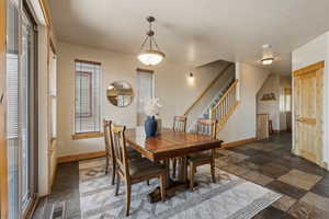 Dining space with baseboards, stairs, and dark stone finish floors