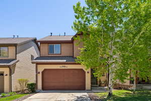 Multi unit property with a garage, driveway, and a shingled roof