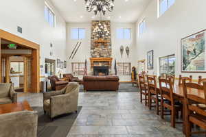 Living area with a towering ceiling, a chandelier, a stone fireplace, and recessed lighting