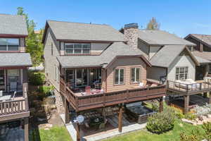 Rear view of house featuring a shingled roof, a chimney, and a deck