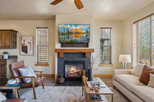 Living room featuring baseboards, a tiled fireplace, and a ceiling fan