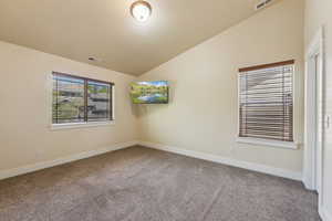 Spare room with carpet flooring, vaulted ceiling, and baseboards