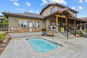 Rear view of property featuring board and batten siding, a shingled roof, a patio area, and stone siding