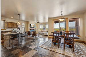 Dining room with healthy amount of natural light, baseboards, recessed lighting, ceiling fan, and a warm lit fireplace