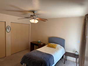 Carpeted bedroom featuring ceiling fan and multiple closets