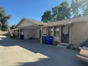 View of front facade with a carport, brick siding, and concrete driveway