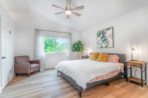 Bedroom with lofted ceiling, light wood-style floors, baseboards, and ceiling fan