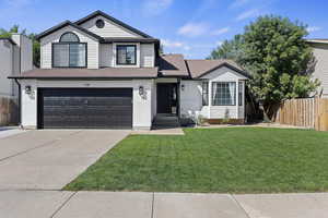 Traditional home featuring a garage, driveway, brick siding, and a shingled roof