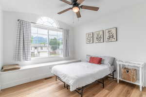 Bedroom featuring vaulted ceiling, wood finished floors, and a ceiling fan