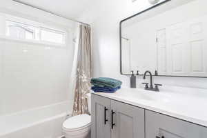 Bathroom featuring vanity, shower / tub combo, and toilet