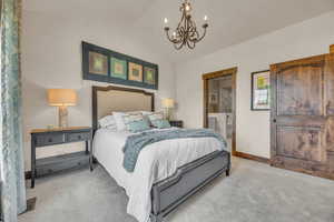 Bedroom with light carpet, a chandelier, vaulted ceiling, baseboards, and connected bathroom