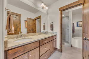 Bathroom featuring tile patterned floors, double vanity, a garden tub, and tiled shower