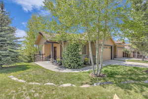 View of front of house featuring an attached garage, stone siding, board and batten siding, and driveway