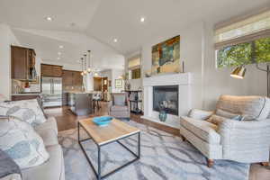 Living area featuring lofted ceiling, wood finished floors, recessed lighting, and a glass covered fireplace