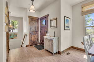 Entrance foyer with light wood-style flooring, a chandelier, and baseboards