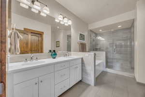 Bathroom with double vanity, a stall shower, a garden tub, tile patterned flooring, and recessed lighting