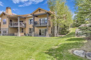Back of property featuring stone siding, a balcony, and board and batten siding
