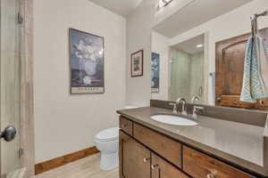 Bathroom with vanity, a shower stall, toilet, and baseboards