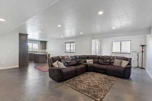 Living area with finished concrete floors, recessed lighting, baseboards, healthy amount of natural light, and a textured ceiling