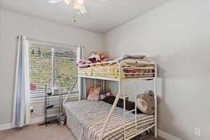 Carpeted bedroom featuring baseboards and ceiling fan