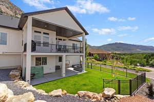 Back of property with a balcony, a mountain view, a patio area, and stucco siding