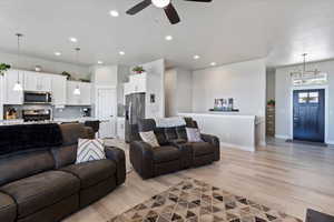 Living area with light wood-style floors, ceiling fan, baseboards, recessed lighting, and a chandelier